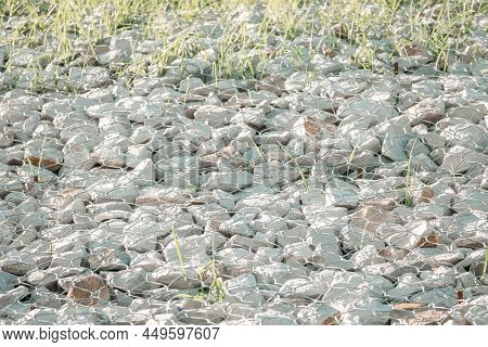 Green Grass In Granite Stones Behind A Metal Grate For Strengthening The Slope. Stones Behind The Wi