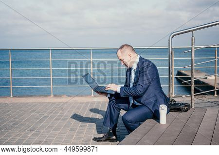 Confident Middle Age Businessman Working Remotely Online, Typing On A Laptop Keyboard While Sitting 