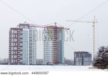 High-rise Buildings Under Construction With Red And Yellow Building Cranes Under Falling Snow In Win