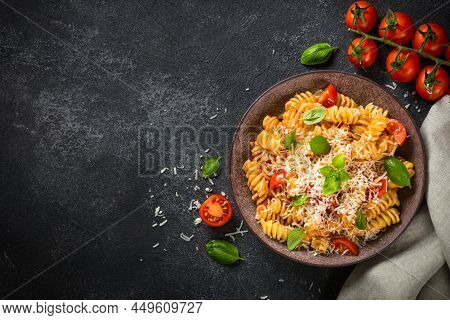Italian Pasta Alla Arrabiata With Basil And Parmesan Cheese On Dark Table. Fusilli Pasta With Tomato