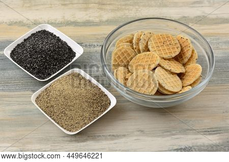 Black Pepper And Poppy Seed Wafer Cookies In Glass Bowl With Poppy Seeds And Black Pepper On Two Sma