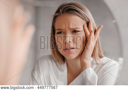 Mirror Reflection Of Upset Lady Looking At Mirror And Touching Her Forehead, Having Dry Skin Problem
