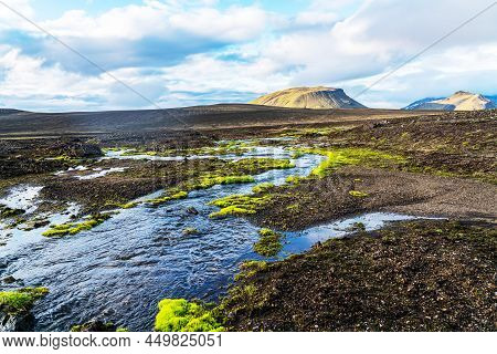 Beautiful Mountain Landscape In Highland With Green Moss Around The Blue Stream And Rough Lava Rocks