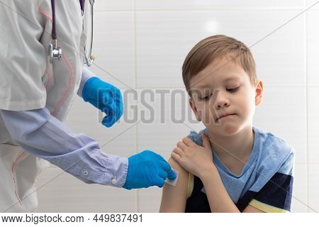A Doctor In A White Medical Coat And Rubber Gloves With A Phonendoscope Makes A Coronavirus Vaccinat