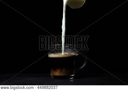 Cream Is Poured Into Coffee On A Black Background. Tonic Coffee Drink. Coffee With Milk