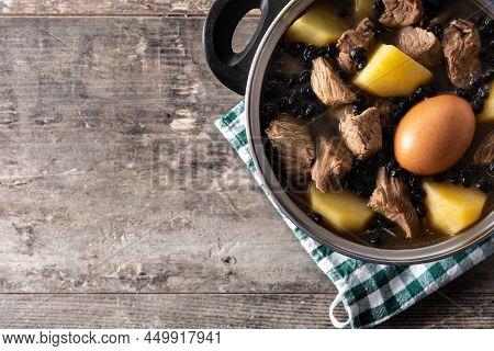 Traditional Jewish Cholent In Casserole On Wooden Table. Top View. Copy Space