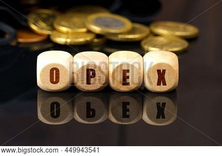 Business And Economy Concept. On A Black Reflective Surface Are Coins And Wooden Cubes With The Insc