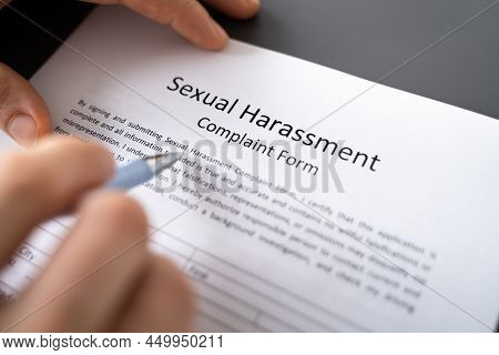 Close-up Of A Human Hand Filling Sexual Harassment Complaint Form With Pen