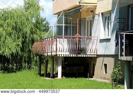 Dilapidated Old Concrete Balcony Supported By Four Concrete Columns At The Edge Of Suburban Apartmen
