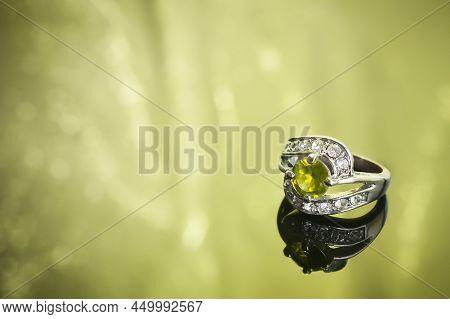 Luxurious Ring Of Diamonds And Olivine, On A Reflective Surface With Reflections, Horizontal Frame, 