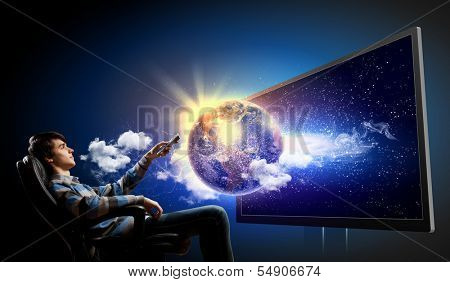 Young man in armchair with click watching TV