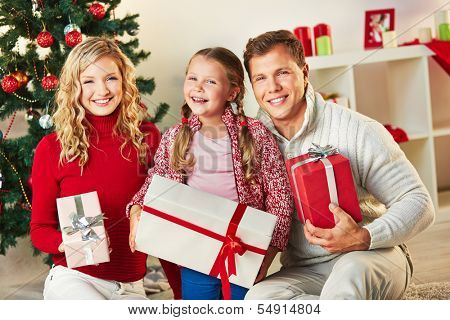 Portrait of happy family with giftboxes looking at camera on Christmas day