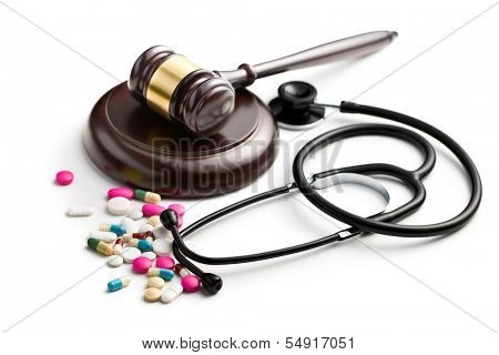 judge's gavel with stethoscope and pills on white background