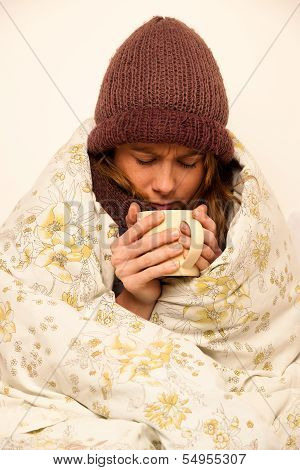 Ill Woman With Feaver Drinking Cup Of Warm Tea Under Blanket