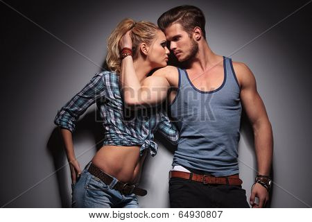 casual sexy man embracing his woman and reveals his biceps, studio shot