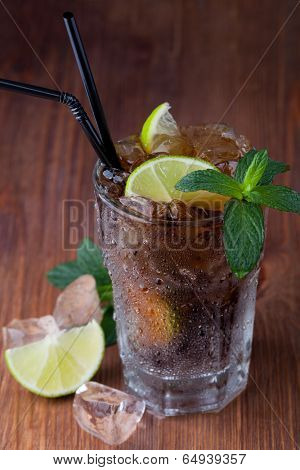 Cuba Libre Drink with lime on a wooden table
