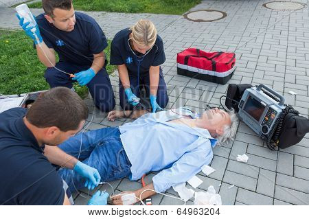 Emergency team giving firstaid to injured elderly patient on street