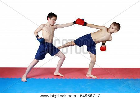 Two athletes are training in shorts kick low kick on the mat