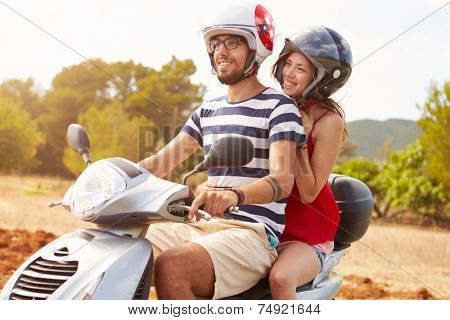 Young Couple Riding Motor Scooter Along Country Road