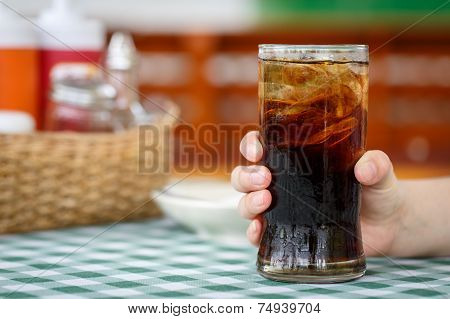Hand Holding Glass Of Cola Drink On Table