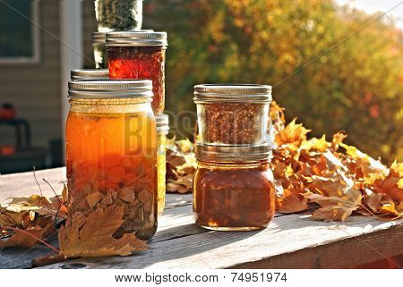 Jars of home canned food on a picnic table in autumn