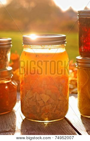 Glass jar of home canned chicken soup in autumn sunlight