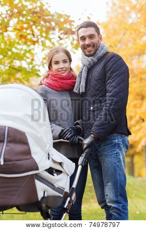 love, parenthood, family, season and people concept - smiling couple with baby pram in autumn park