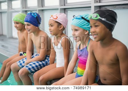 Cute swimming class smiling poolside at the leisure center