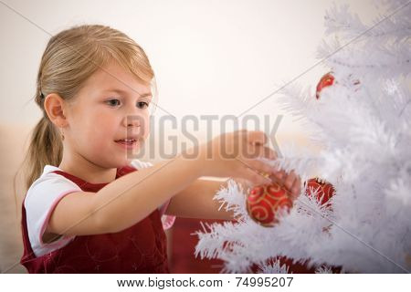 Little girl decorating white christmastree