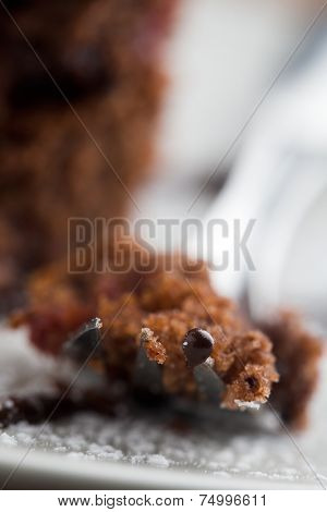 Piece of strawberry-chocolate cake on fork, focus on tip of the fork