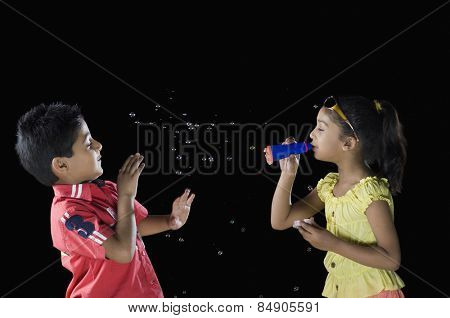 Girl blowing bubbles towards a boy
