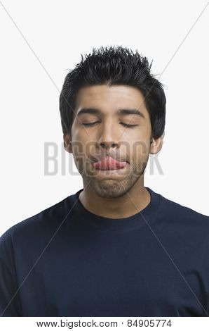 Close-up of a man licking his lips with eyes closed