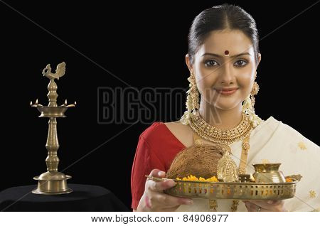 Portrait of a South Indian woman holding a plate of religious offerings