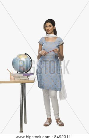 Female teacher holding a pen near a desk