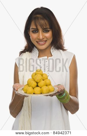 Woman holding Laddu in a plate on Holi