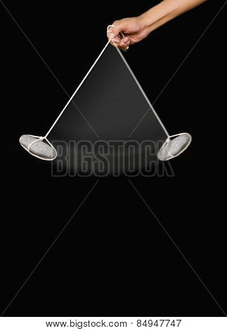 Close-up of a person's hand swinging a stone pendulum