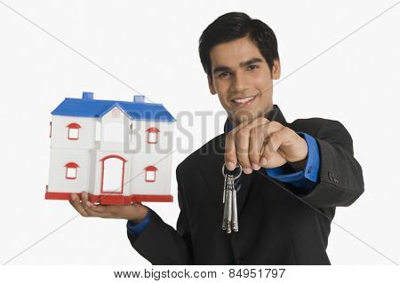Real estate agent holding house keys and a model home