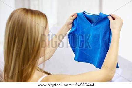 motherhood, people and kids clothing concept - happy woman holding and looking at little boys blue pullover at home