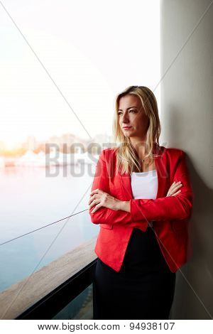 Portrait of confident businesswoman looking out of an office balcony with beautiful seaport view