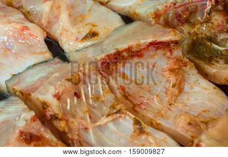 Pieces of carp fish in oil ready for cooking with spices