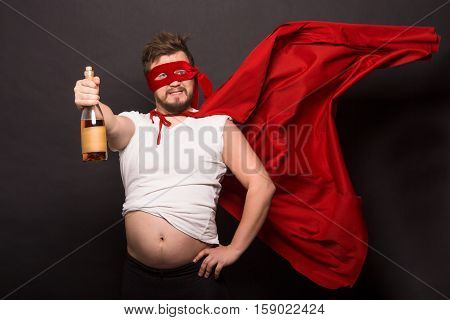 Super anti hero man showing bottle with wine or whiskey while drinking alcohol isolated on black background. Handsome man is bad man.