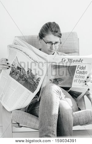 PARIS FRANCE - NOV 29 2016: Woman reading Le Monde newspaper with headline and articles about Fidel Castro Cuban President - dead on November 25 2016 - black and white