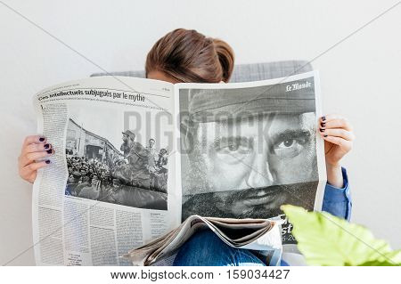 PARIS FRANCE - NOV 29 2016: Woman reading Le Monde newspaper with headline and articles about Fidel Castro Cuban President - dead on November 25 2016