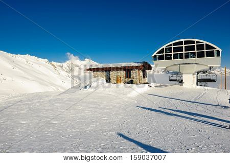 Ski lift station in mountains at winter. Alpine winter mountain landscape. French Alps covered with snow in sunny day. Val-d'Isere, Alps, France