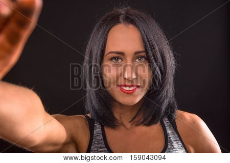 Fitness or sports concept. Happy smiling fitness lady making self photos on her mobile or smart phone while posing for photographer in studio.