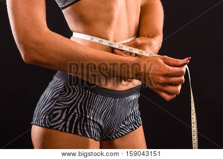 Slim, slender, dieting concepts. Fitness lady using meter stick for her body. Lady measuring her waist after or before training in studio.