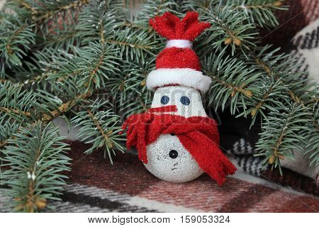 Snowman made from light bulb near Christmas tree