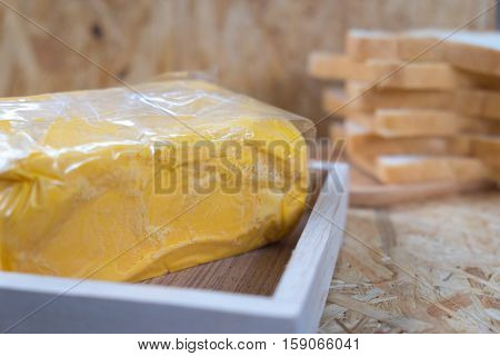 Piece of butter on wood tray with sliced bread background