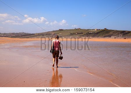 LIENCRES DUNES SPAIN - AUGUST 21: Woman walking in the water edge of the Liencres dunes nature reserve in the Cantabrian sea on August 21 2016