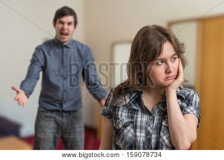 Argue of young couple. Angry man is arguing and sad woman is ignoring him.